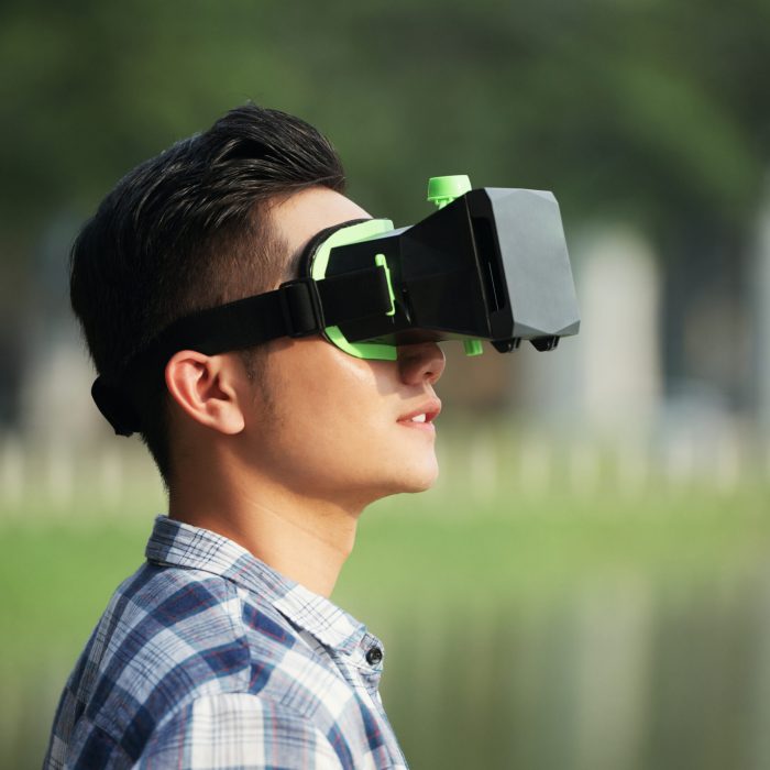 Young Vietnamese man in vr goggles standing in the street